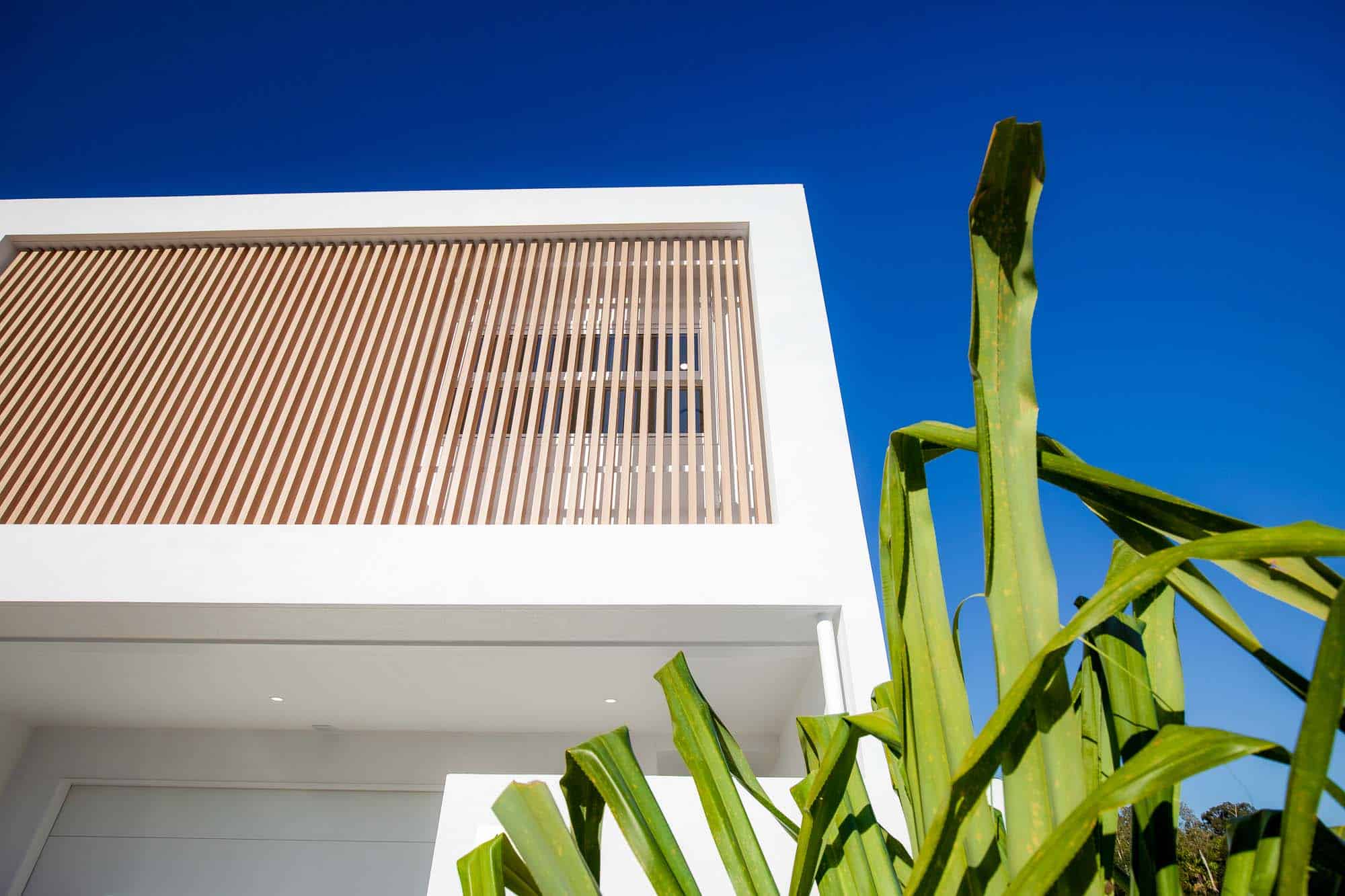 White rendered custom home with vertical timber battens, built by FEZ Constructions on the Sunshine Coast
