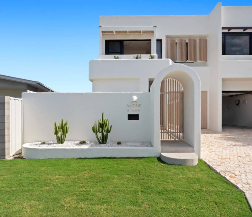 White rendered coastal home with arched entry